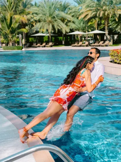 A couple takes a playful plunge into the pool, a spontaneous and fun moment from a pre-wedding pool party.