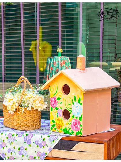 Detail is everything. This hand-painted birdhouse, paired with a basket of fresh flowers and a floral tablecloth, is an example of the small, thoughtful touches I add to make a theme feel complete.