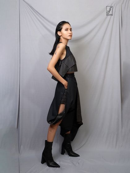 A full-length profile shot that displays the asymmetrical design and unique silhouette of the entire outfit.