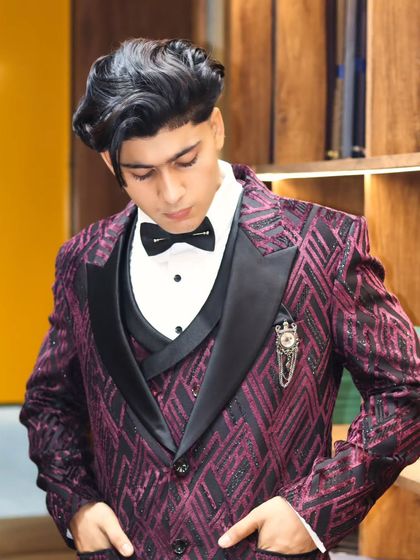 A close-up of the purple and black patterned three-piece suit. The intricate design of the fabric combined with the classic tuxedo structure makes it a true statement piece.