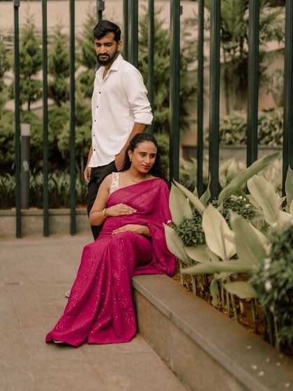 A quiet moment of togetherness. This portrait captures the couple in a peaceful, seated pose, highlighting the protective and loving way he holds her as she cradles her bump.