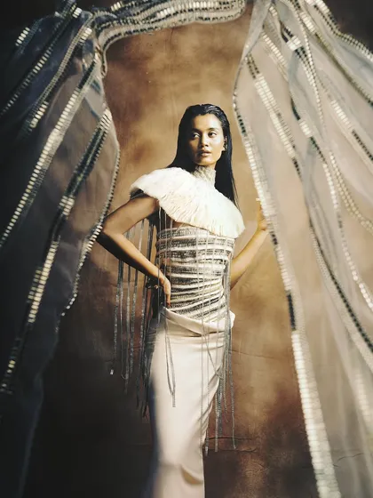 An ethereal, high-fashion look with earthy tones and intricate textures. The makeup is kept neutral to let the avant-garde outfit shine.