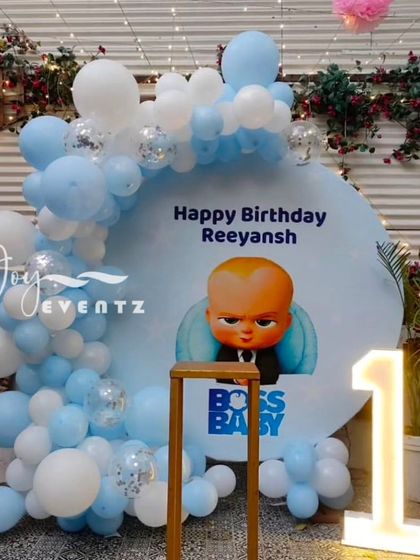 For Reeyansh's first birthday, I designed this simple yet charming Boss Baby setup. It features a circular backdrop with the birthday boy's name, a pastel blue and white balloon half-arch, and a light-up marquee number '1'.