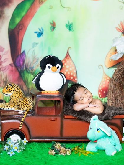 A sleepy newborn on a safari adventure, resting in the back of a truck surrounded by jungle animals.