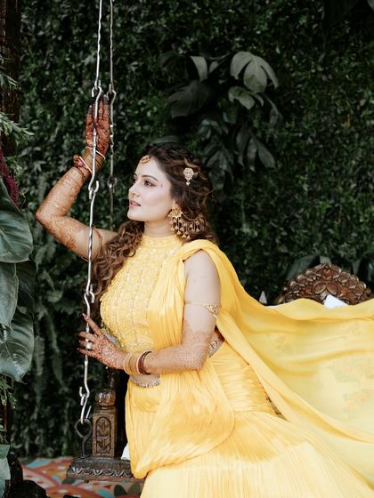 A graceful pose by the bride on a traditional swing, framed by lush greenery. This setup was designed to have a 'Shakuntala' inspired, ethereal feel.