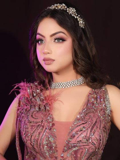 A soft and romantic party look with a pink feathered dress and a delicate tiara. This showcases the versatility of our students' skills.