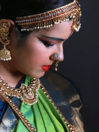 A pensive profile shot of the dancer, highlighting her elaborate makeup and the beautiful details of her costume and hair adornments. The soft lighting creates a dramatic, focused mood.