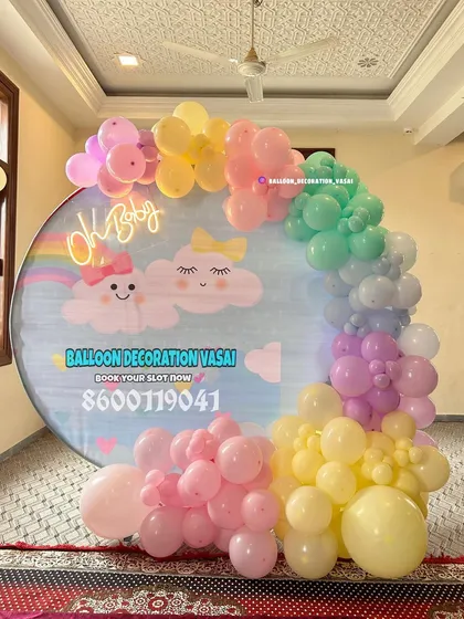 A whimsical "Oh Baby" design with a pastel rainbow balloon arch and a custom backdrop featuring cute, smiling clouds. This theme is perfect for creating a light, happy, and dreamy atmosphere.
