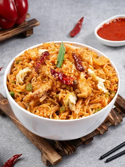 A bowl of spicy fried rice, styled with fresh ingredients in the background. This helps to tell the story of the dish and its flavors.