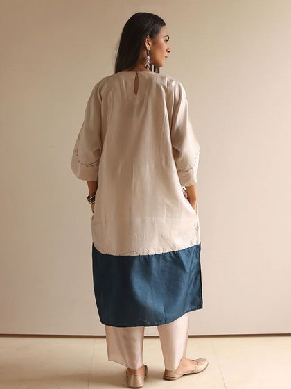 The back view of a color-blocked kurta, combining a neutral beige top with a solid navy blue panel at the hem for a modern twist.