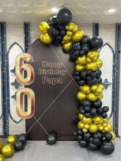 This is a duplicate of ID 134. A classic and stylish 60th birthday decoration for a father. This simple setup features a black arched backdrop with 'Happy Birthday Papa' and a sophisticated black and gold balloon garland.