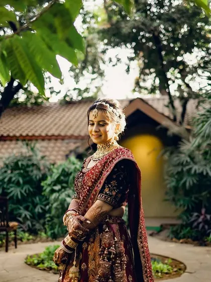 A beautiful outdoor portrait of the bride in her wedding lehenga. The natural setting and her serene expression create a peaceful and elegant image.