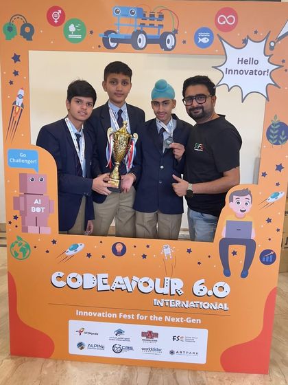 A winning team from the Codeavour 6.0 Nationals poses in the "Hello Innovator" photo booth with their trophy and mentor.