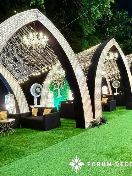I designed these arched cabanas for a bohemian-themed Sangeet. The intricate laser-cut panels, string lights, and comfortable lounge seating create stylish and semi-private spaces for guests to relax.