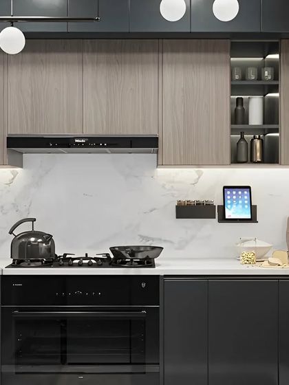 A close-up of a modern kitchen setup, featuring sleek grey cabinets, a white marble backsplash, and integrated black appliances for a seamless look.