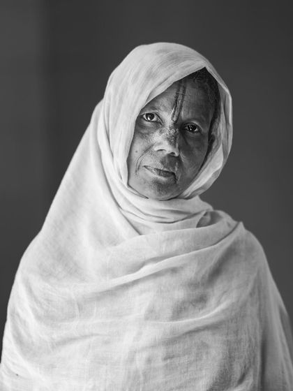 A black and white portrait of a woman from the 'Widow Holi' celebrations in Vrindavan, her expression conveying resilience and a quiet dignity.