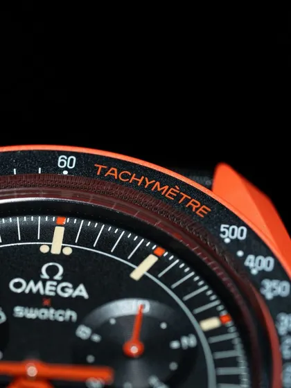 A macro view of the orange "Tachymètre" text on the bezel, a detail that ties into the watch's overall color scheme.