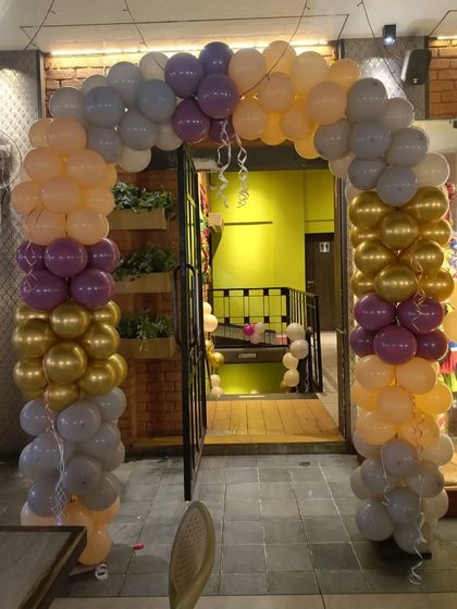A colorful balloon arch at the entrance of a venue. The mix of pastel, purple, and gold balloons creates a festive welcome for baby shower guests.