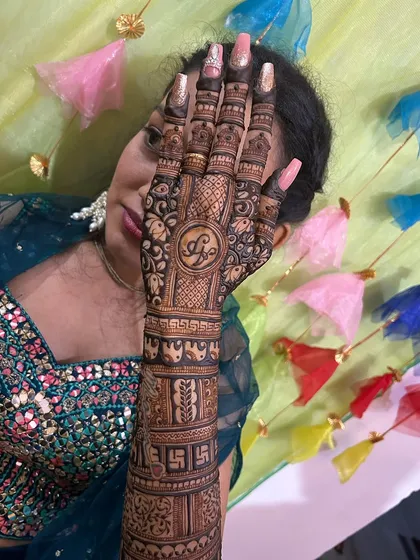 A happy bride showing off her intricate back-hand design, which features her initial "A" in a beautiful mandala.