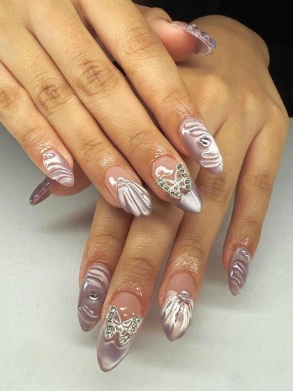 An imaginative design featuring sculpted shells and silver butterfly charms. This showcases the creative possibilities when you master 3D nail art techniques.