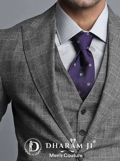 A close-up of a grey three-piece suit. The subtle check pattern of the fabric and the contrasting purple tie create a refined and professional look.