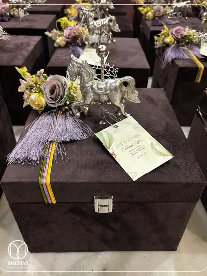 A close-up of a royal-themed baby announcement hamper, presented in a luxurious deep purple velvet chest. The gift is adorned with a silver-plated horse figurine and a custom 'Thank You' tag, making it a grand and memorable keepsake.