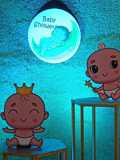 Welcoming a new arrival with a cute baby shower theme. This decoration features a custom 'Baby Shower' light, a green turf backdrop, and adorable cartoon baby cutouts.