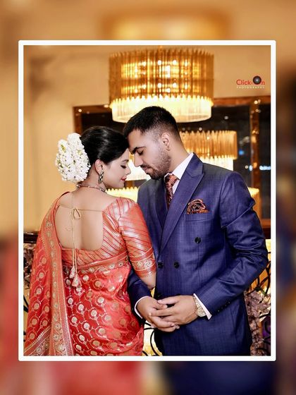 An elegant reception or post-wedding portrait. The warm lighting from the chandelier adds a touch of glamour to this intimate couple shot.