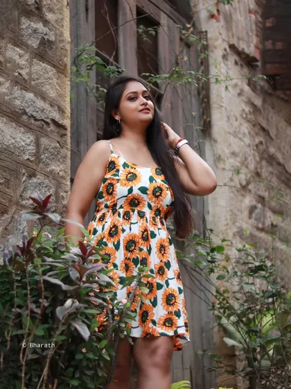 A portrait of the same model and dress, set against a rustic stone wall.