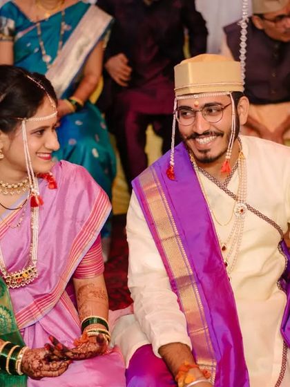The bride and groom sharing a smile, seated together during their Maharashtrian wedding ceremony.