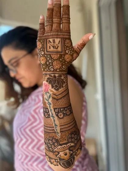 A personalized design with the client's name 'Sangeeta' written beautifully on the arm, along with their initials 'NV'.