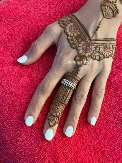 A very chic and minimal design focusing on a single finger. The pattern resembles an ornate ring, connected by a delicate chain to a simple wrist cuff, perfect for a modern party look.