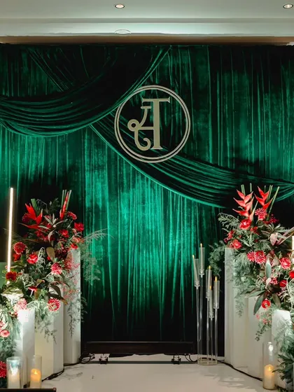 It's the personal touches that make a wedding truly yours. For this modern luxe reception, I created a dramatic photo backdrop with rich emerald velvet, accented by bold red tropical flowers and the couple's custom monogram.