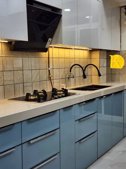 A detailed shot of the hob and sink area, highlighting the high-gloss acrylic finish and the sleek, modern hardware.