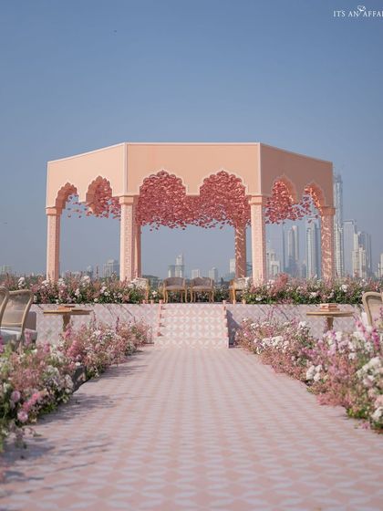The breathtaking mandap set against the Mumbai skyline. The structure is a modern interpretation of a palace pavilion, with a ceiling of pink flowers.