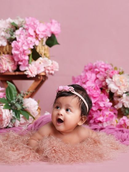 A look of pure wonder from this sweet baby during her milestone session. The soft pink tones and floral arrangements create a dreamy and gentle atmosphere.