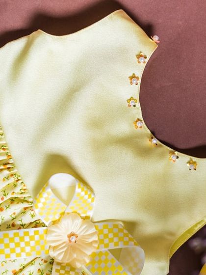 A closer look at the details of this lemon-yellow dress. The neckline is hand-beaded, and the floral print skirt is made from a lovely, lightweight cotton.