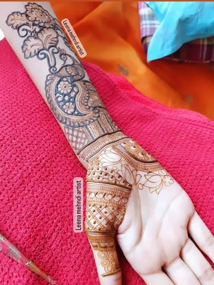 The start of a beautiful peacock design on the forearm. This shows the clean outline work that forms the foundation of the pattern.