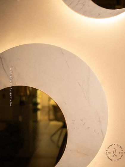 A modern wall sconce featuring a disc of white marble with a gold-mirrored circular cutout. The backlight provides a soft, ambient halo, making it a sophisticated and elegant choice for hallways or flanking a master bed.