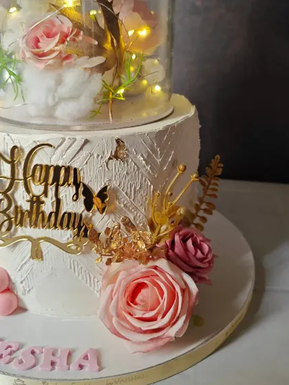 A close-up of the beautiful details on the 10th birthday cake, showing the intricate textures, gold butterflies, and fresh roses.