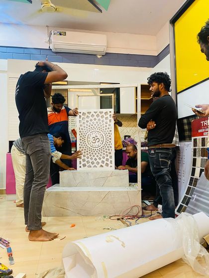 Our team carefully assembles a custom pooja mandir at our office. This image captures the moment we install the beautiful 'Om' panel, a centerpiece of the design.