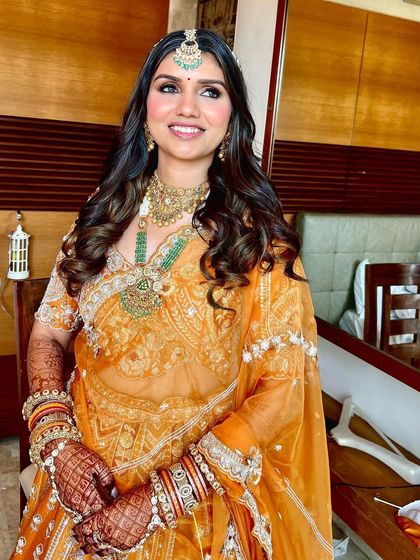 The complete Phera look. The orange lehenga, intricate jewelry, and soft, glamorous makeup create a stunning bridal vision.