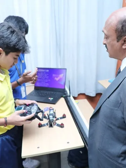 A student demonstrates his remote-controlled robot to a guest. This hands-on demonstration is a powerful way for students to showcase their understanding of electronics and programming.