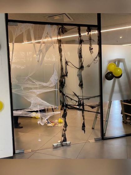 To enhance the Fear Factor theme, we decorated a glass door with spooky spiderwebs and balloon clusters, adding to the suspenseful and fun atmosphere.