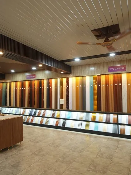 This is our main display wall, showcasing a massive range of WPC louvers and panels in different colors, textures, and finishes. The backlighting helps you see the true look of each material.