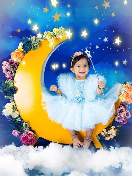 A fairy on the moon. This magical setup combines a celestial theme with fairy elements, featuring a little one in a beautiful blue dress with a star wand.