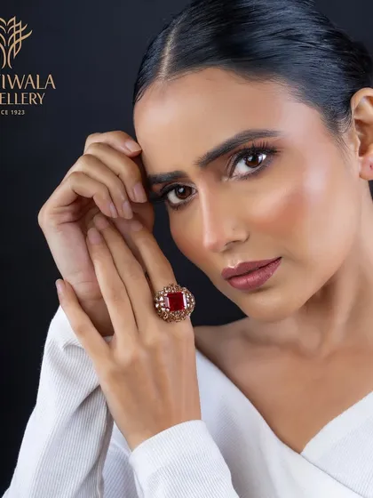 A traditional design with a modern twist. This ring features a central square-cut ruby set in an ornate, diamond-studded gold mounting.