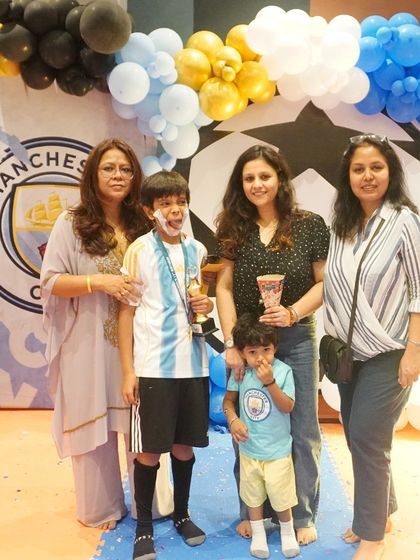 Another happy family photo, capturing the joy of the birthday boy with his trophy and loved ones.