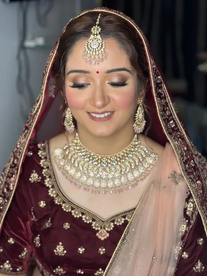 My bride Priyanka, looking absolutely regal in a deep maroon velvet lehenga. I opted for a soft glam eye and a warm nude lip to complement the richness of her outfit.