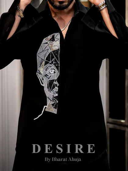 Art meets attitude. This close-up shows the intricate, geometric embroidery of an abstract face on a classic black shirt.